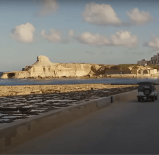 A car drives by the coast.