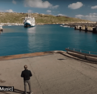 A man stands on a dock as a large ferry approaches.