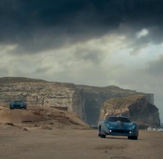 A group of cars parked on a rock beach.