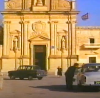 Cars parked in front of a church.