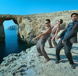 A group of men dancing on a cliff overlooking the Azure Window.