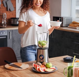 a woman is standing in front of a blender