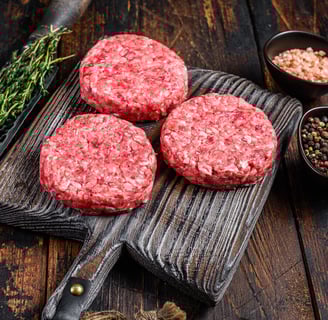 three uncooked hamburger patties on a cutting board