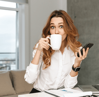 a woman sitting at a desk with a cup of coffee