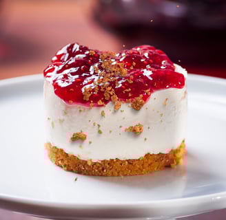 Mini cheesecake cups topped with fresh raspberries and a dusting of graham cracker crumbs