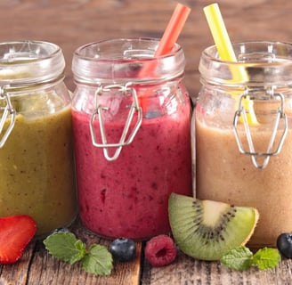 three jars of fruit smoothies with fruit and strawberries