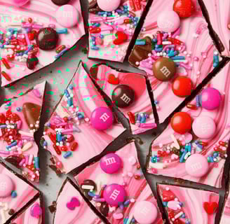 A colorful sheet of Valentine’s Day bark broken into irregular pieces, with pink swirls, M&M's, and