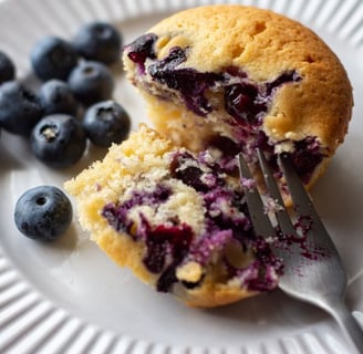 A white plate with a Wild Blueberry Muffin on it