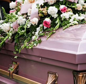 a off pink coffin with a casket sprays of cornations and roses