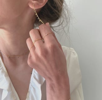 Photo bijoux BYNORA portés. Chaîne d'oreilles, bagues, sautoir et bracelet avec des diamants bruts multicolors