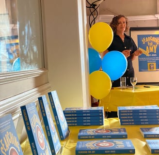 photo of a book launch with books on a table and balloons