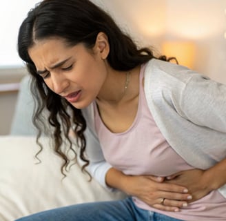 "Mulher tocando o lado direito do abdômen com expressão de desconforto leve, indicando dor hepática."