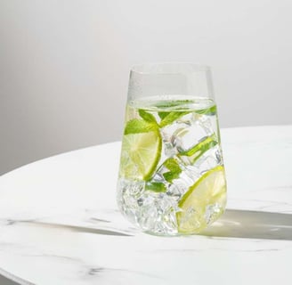 Copo de água com limão sobre mesa iluminada pela manhã