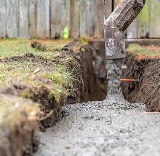 a concrete slab being poured into a trench