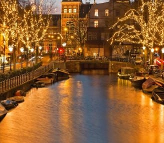 Amsterdam - a river with boats and christmas lights on it