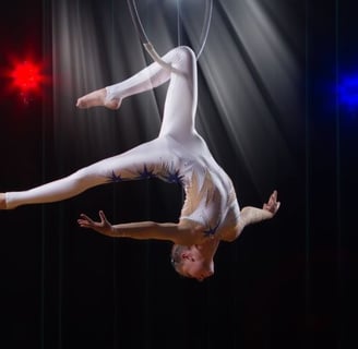 a woman in white and blue outfit performing a trick on a hoop