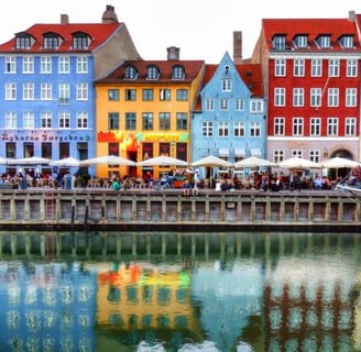 a group of people sitting at tables near a body of water