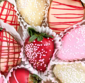 a box of chocolate covered strawberries with white and red sprinkles