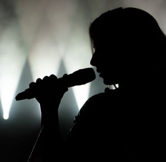 a woman singing into a microphone in front of a stage