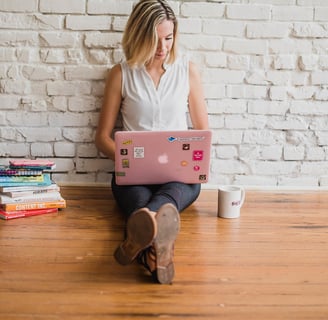 a woman sitting on a wooden floor with a laptop computer