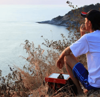 a man sitting on a hill with a tablet computer