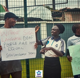 Photo of 2 Deaf persons - a man and a woman - communicating in Sign Language