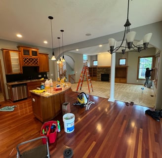 a kitchen with a wooden floor and a ladder with two cleaners