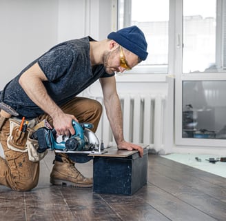 a man in a blue hat and a blue hat is holding a circular sawdust