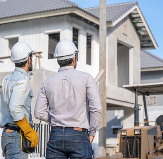two men in hard hats standing in front of a house