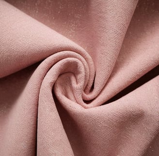A close-up shot of a recycled polyester material. The material is a soft pink hue and has a subtle texture
