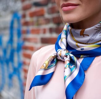 A photo of a woman wearing a printed silk scarf. The scarf is wrapped around her neck and tied with a bow at the front