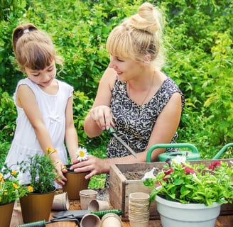 Mujer y niña sembrando flores en un jardín lleno de vida