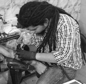 About us page showing tattoo artist tattooing ink on a client, against the mission section