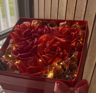 a person holding a red box with roses in it