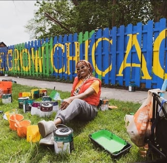 Painter sitting in front of mural with paint cans