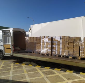 Furgoneta de Transportes Beal cargando pallets con mercancía en un muelle de carga.