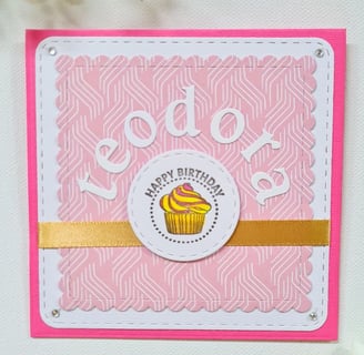Pink birthday card with white border features "Happy Birthday" text and name "Teodora" and a cupcake