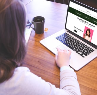 a woman sitting at a table with a cup of coffee and a cell phone, visiting mariadia.store website