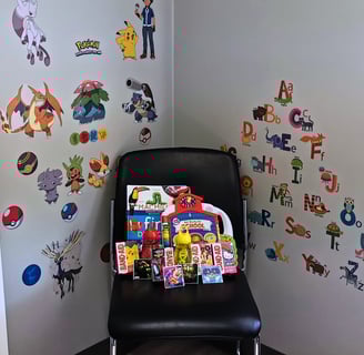 Picture of consult room with stickers on the wall and a chair filled with children's items