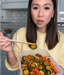 a woman holding a container with vegetables and chopsticks