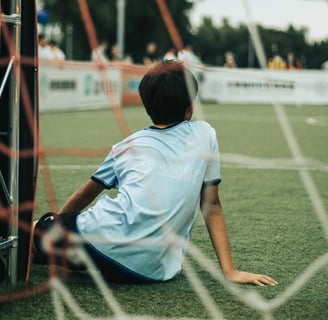 Kid sitting in front of a soccer goal