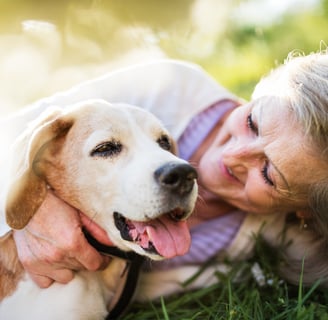 a woman is laying on the grass embracing her dog