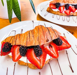 a croissant pastry with fruit on a plate with chocolate sauce