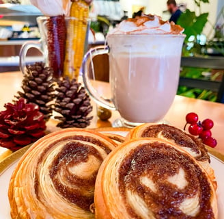 a plate with cinnamon roll pastry with a cup of strawberry tea latte