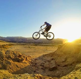Mountain biker hitting a canyon gap jump at sunrise, showcasing advanced freeride technique