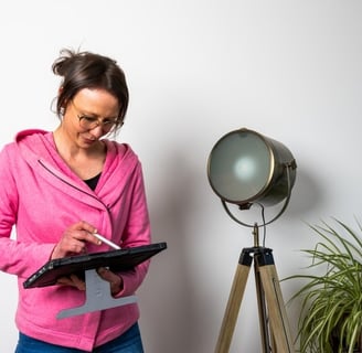 a woman in a pink jacket and jeans standing in front of a lamp