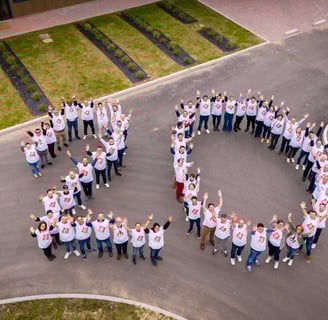 a group of people standing in a circle with a large heart shaped sign