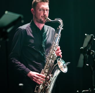 un homme en chemise noire jouant du saxophone