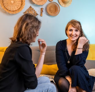 une femme assise sur un canapé parlant à une autre femme