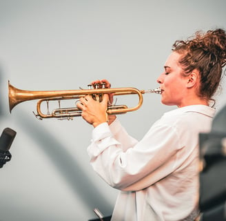 une femme en chemise blanche et trompette au Festival de Jazz de Saint-Omer